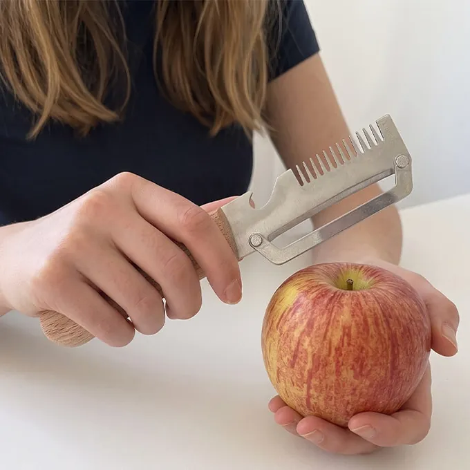 Une femme épluche une pomme rouge avec PeelPro